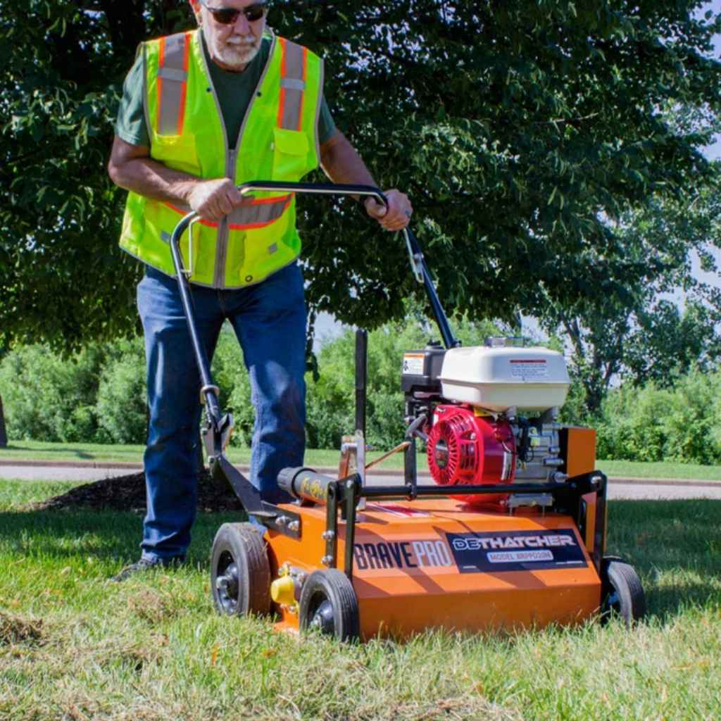 Person operating a BravePro Power Rake Dethatcher 20 inch in an outdoor setting.