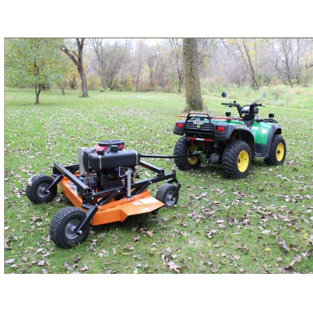 Small ATV pulling a bravepro finish cut pull behind 60 inch mower through a grassy area with trees in the background.