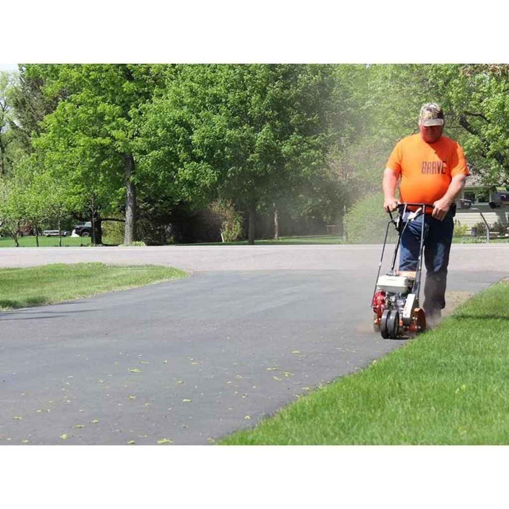 Person using a brave 10 in lawn edger on a grassy area with trees in the background