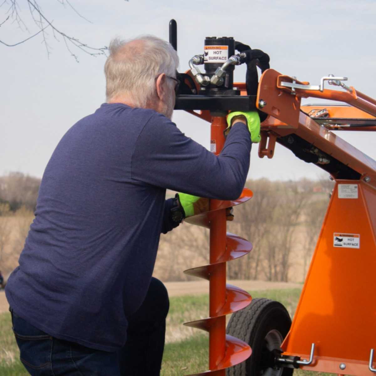 Person operating a Brave pro Towable Auger in an outdoor setting