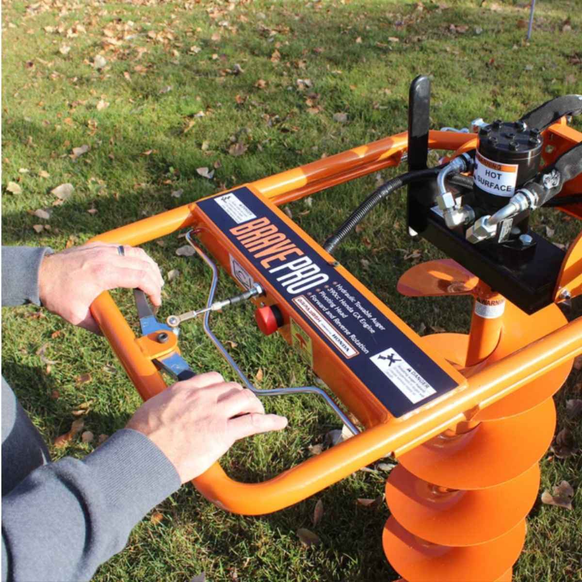 Orange Bravepro Towable Auger with 'Brave Pro' branding on a grassy background