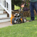 Person using a Brave star blade lawn edger on a grassy area with a house in the background