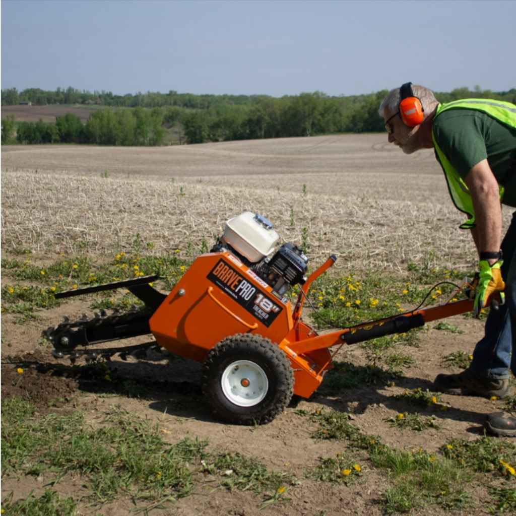 person using an orange brave pro 18 in. trencher on a field