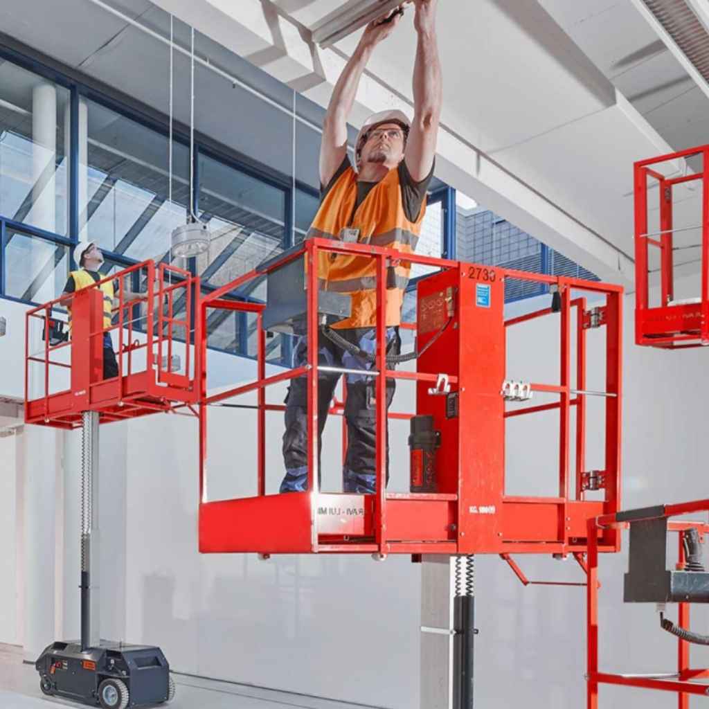 person  reaching a tall structure while on a bravi leonardo scissor lift on a factory setting