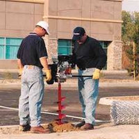 Two workers using a Ground Hog C-17-5 Two-Man Earth Drill on a street.