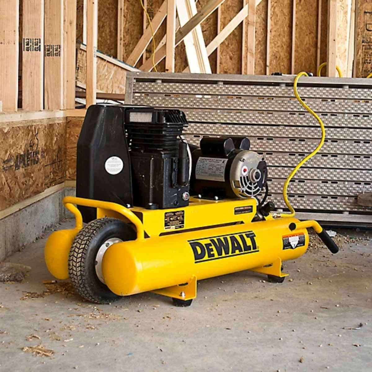 Yellow Dewalt 8 gallon 1.9 hp air compressor in a construction setting with wooden walls and metal shelves.