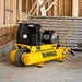 Yellow Dewalt 8 gallon 1.9 hp air compressor in a construction setting with wooden walls and metal shelves.