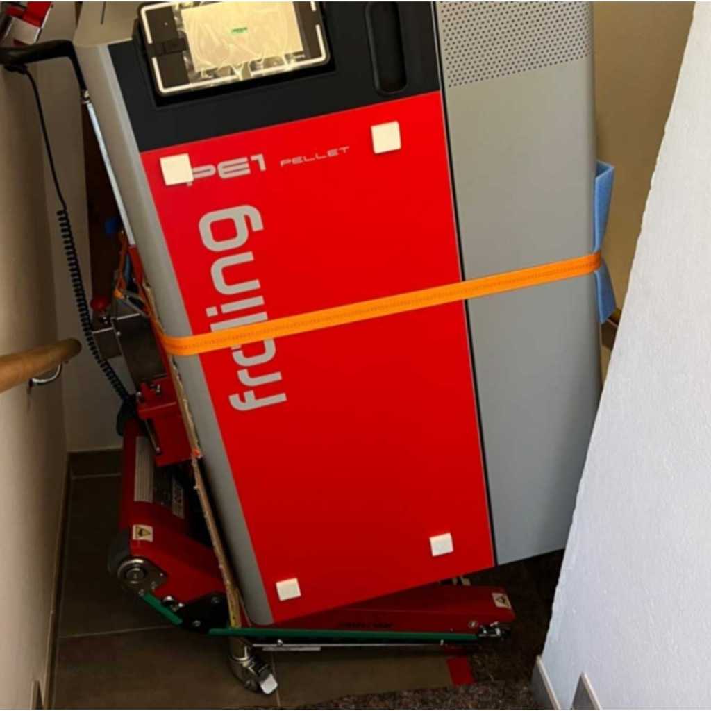 Red Freling pellet stove strapped to a Zonzini Plasmoid stabilized stair crawler with an orange strap in a room setting