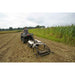 Person operating an ATV with a GreyWolf Chisel Plow & Cultivator 43 In Attached in a field with crops