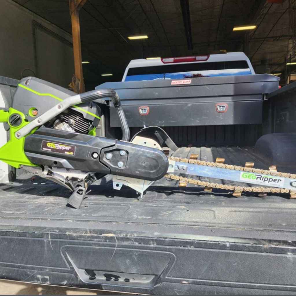a green and black mini trencher georipper in the bed of a truck