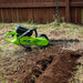 a trench dug in a yard with a mini trencher georipper sitting next to it with a wooden fence in the background during the daytime.