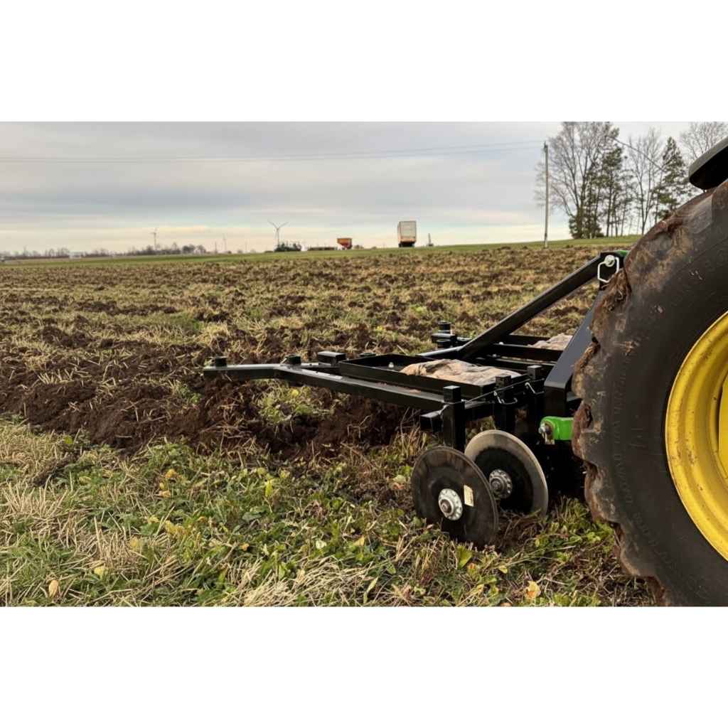Farm tractor plowing a field with a Greywolf till n claw 3 point chisel plow and cultivator with a cloudy sky in the background
