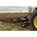 Farm tractor plowing a field with a Greywolf till n claw 3 point chisel plow and cultivator with a cloudy sky in the background