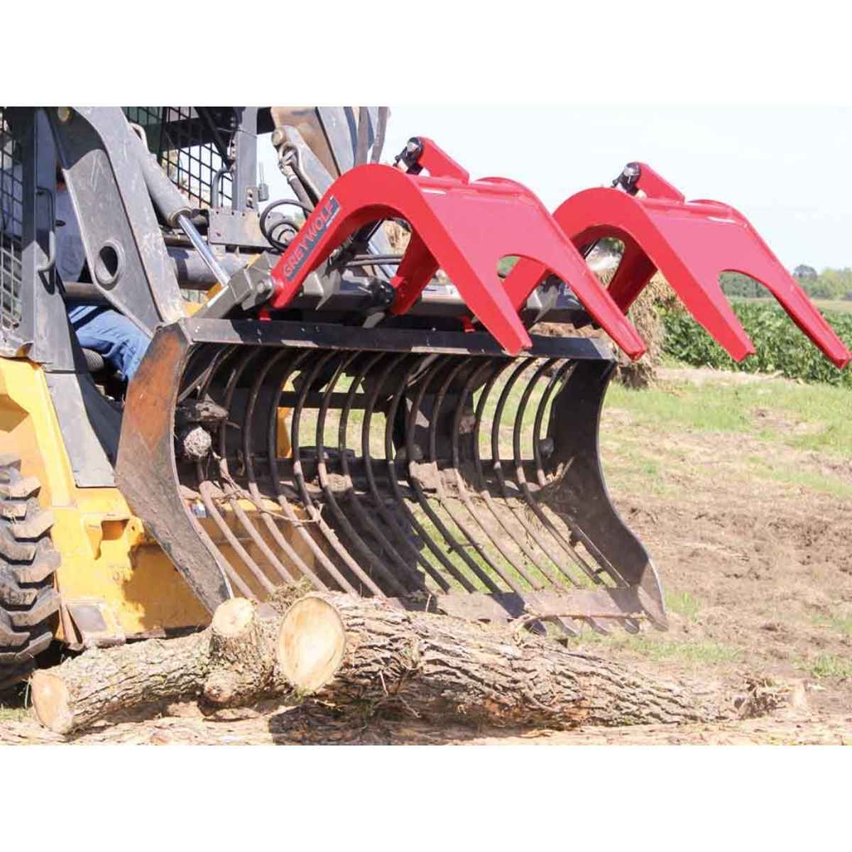 Skid steer loader with a greywolf skid steer quick attach grapple attachment cutting through a log in an outdoor setting.