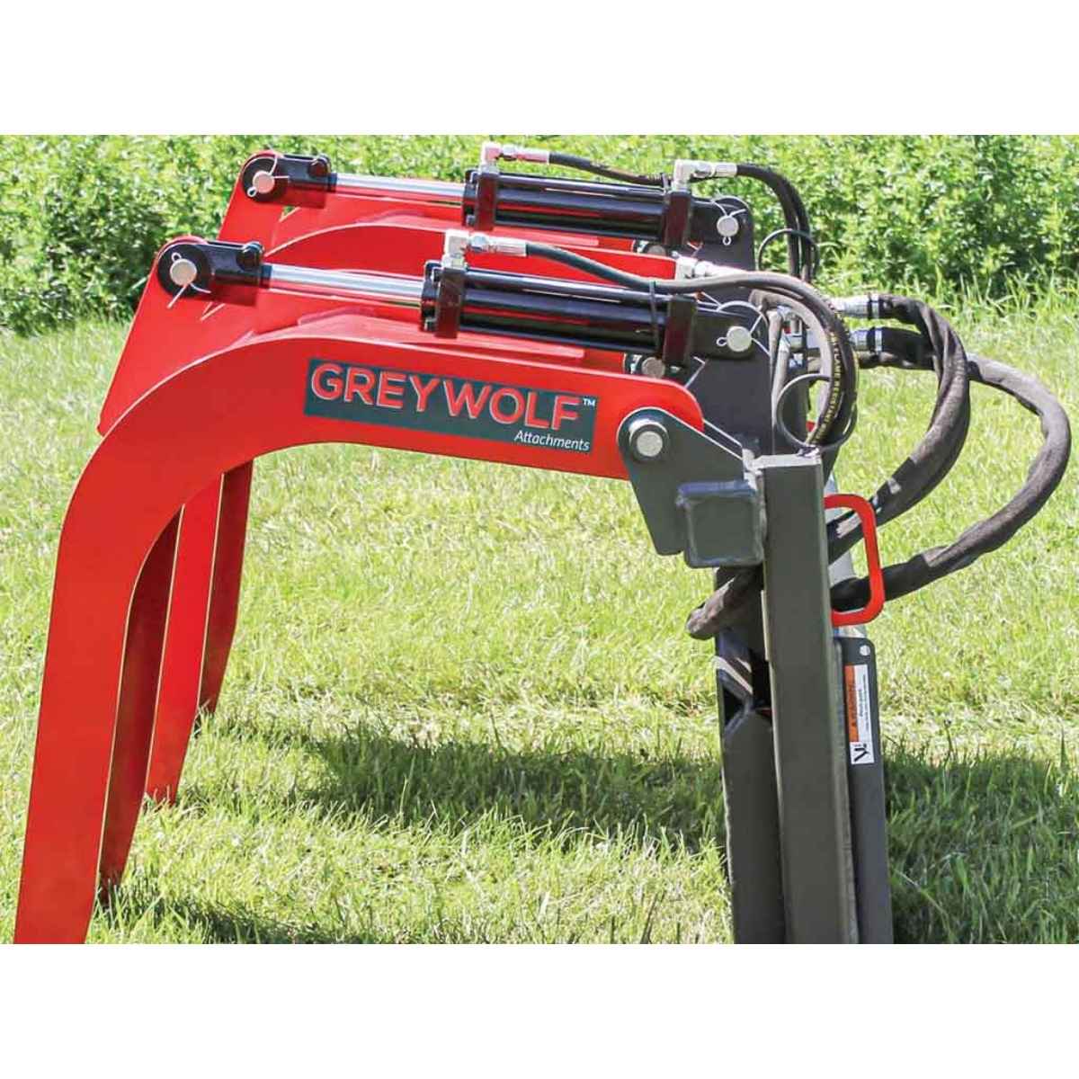 Red greywolf skid steer grapple attachment with 'GREYWOLF Attachments' branding on a grassy background