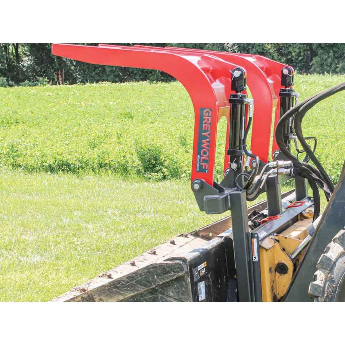 Red Greywolf Grapple quick attach attached to a tractor in a field