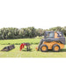 Skid steer loader with greywolf skid steer quick attach grapple attachment on a grassy field with trees in the background