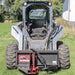 Skid steer loader with Greywolf skid steer tree puller attachment on a grassy field