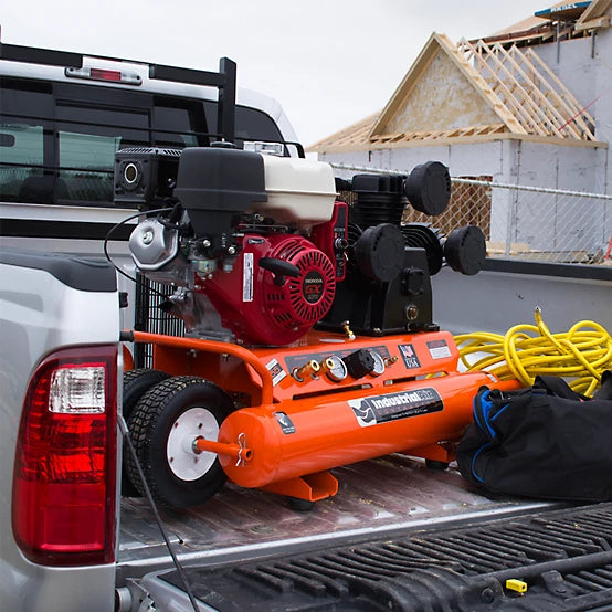 Orange Industrial Air 9 Gallon wheelbarrow air compressor on a truck bed with a construction site in the background