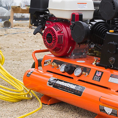 Orange Industrial Air 9 gallon air compressor with visible branding on a construction site