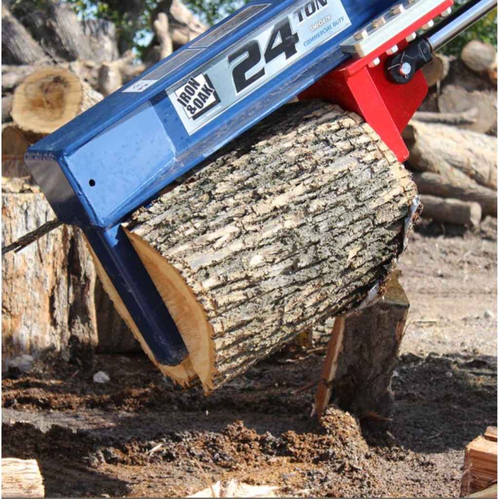 a blue iron and oak 24 ton skid steer mount log splitter holding a log with logs in the background