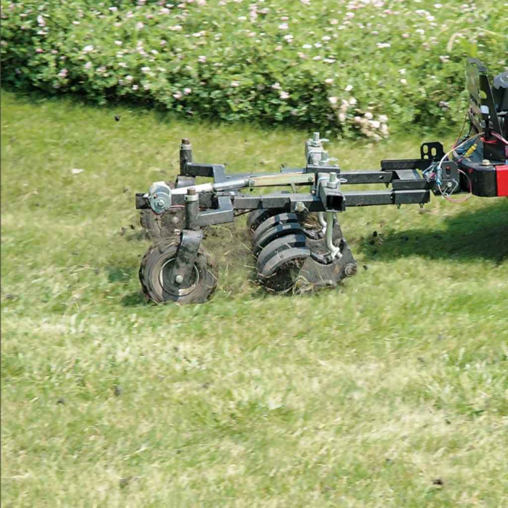 Jrco tow behind 38 inch hooker aerator on a grassy field with flowers in the background