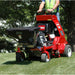 Person operating a jrco 5054 hitch mount spreader in a grassy area with trees in the background