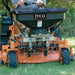 Person operating a jrco 503 spreader labeled 'jrco' in a grassy area