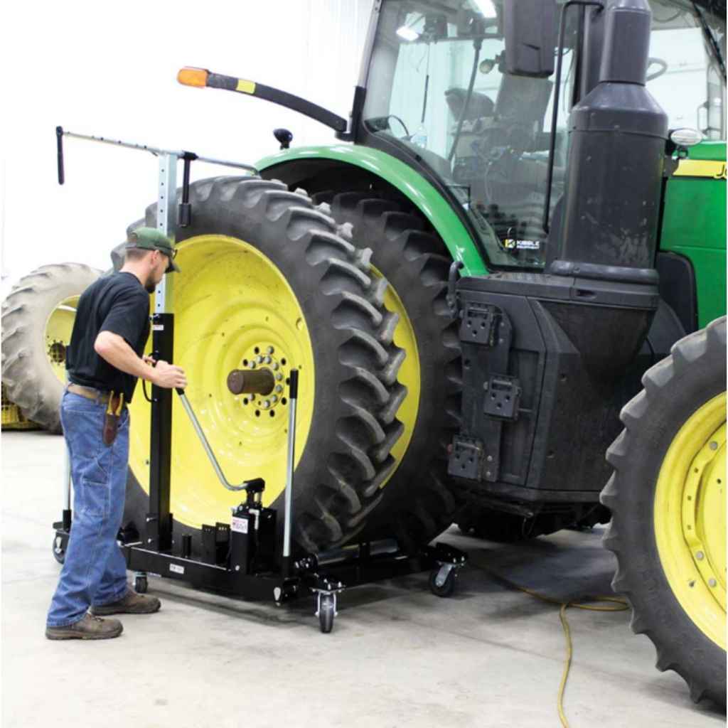 Person working on a large tractor tire on a k and m manufacturing wheel dolly with a tool