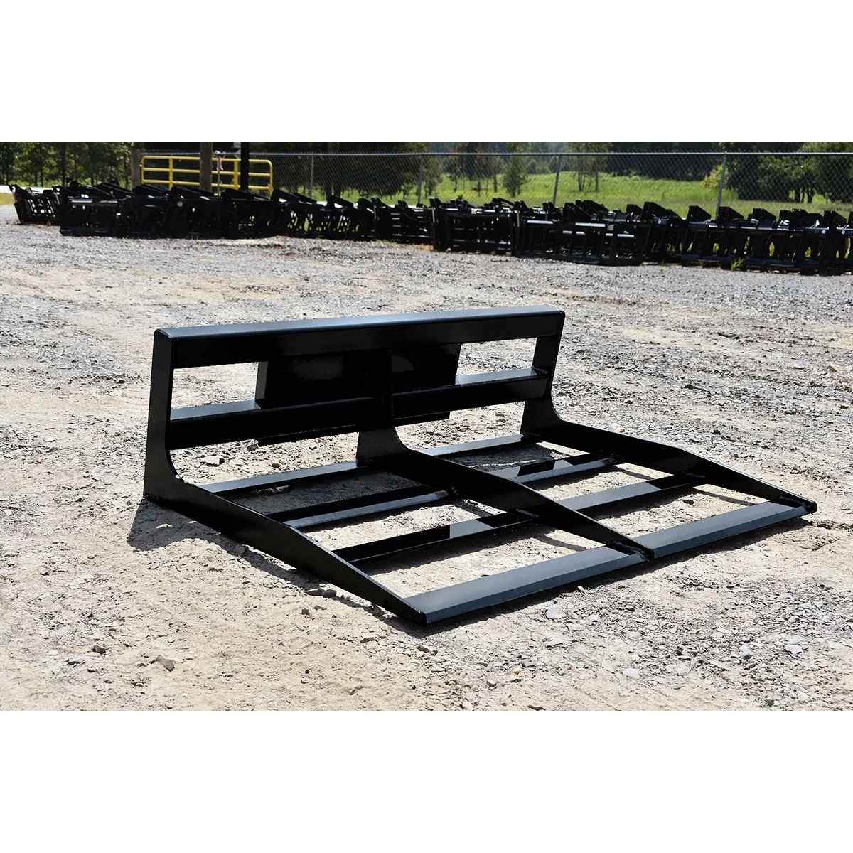 Black Loflin Mini Skid Steer Land Plane on a gravel surface with rows of similar pallets in the background.