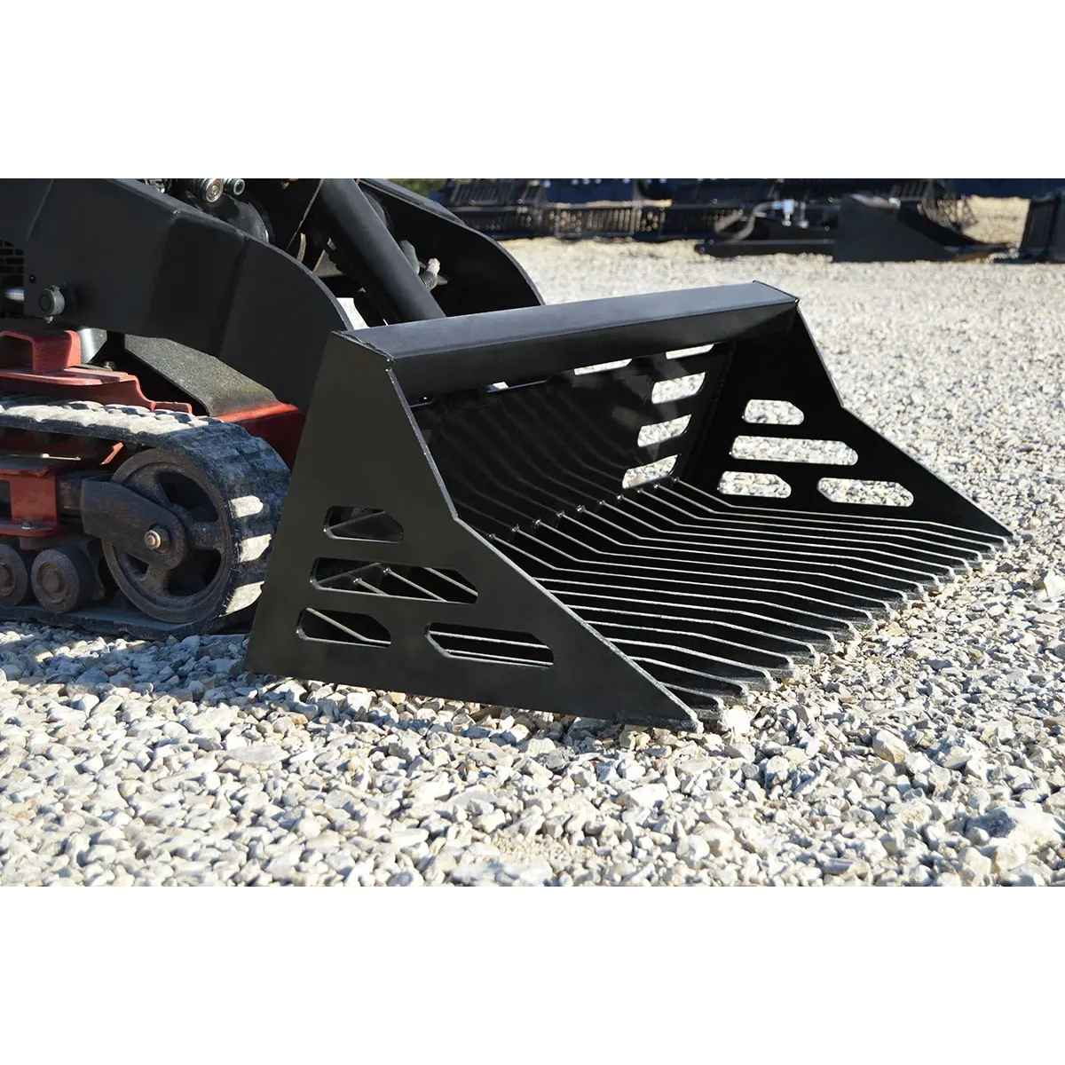 Black Loflin mini skid steer rock bucket on a gravel surface