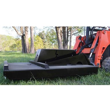 Skid steer loader with a loflin fabrication closed front brush cutter on grassy area with trees in the background