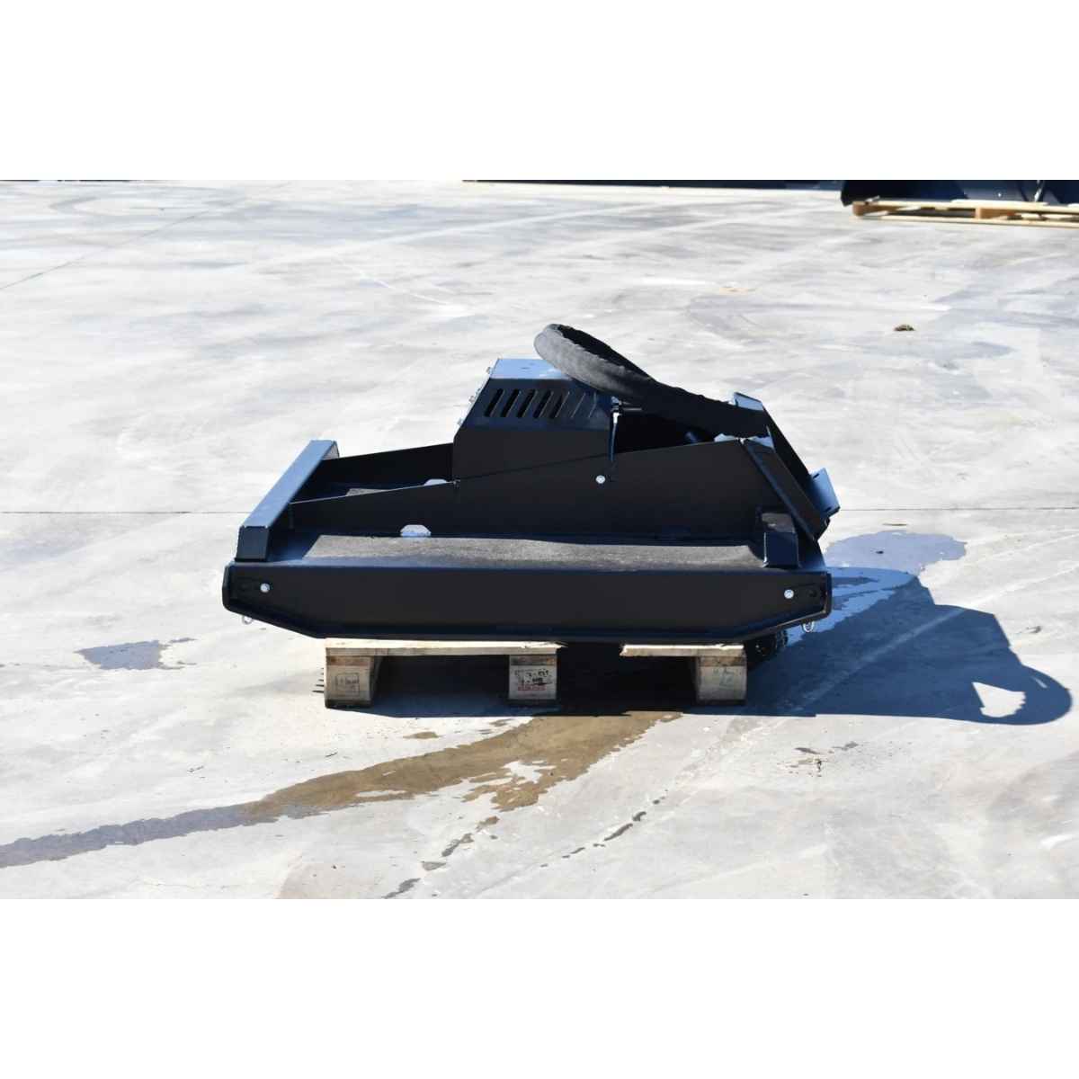 A black loflin mini skid steer brush cutter, resting on a wooden pallet on a light gray concrete surface.