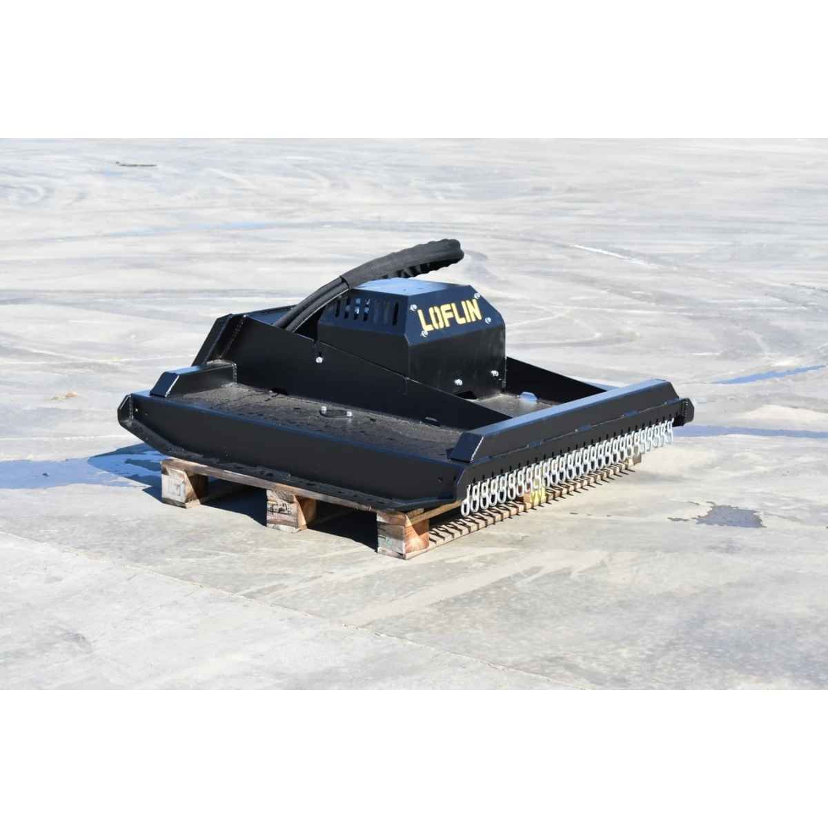 A black Loflin Mini skid steer brush cutter with the brand name 'LOFLIN' in yellow on the side, resting on a wooden pallet over a light gray concrete surface.