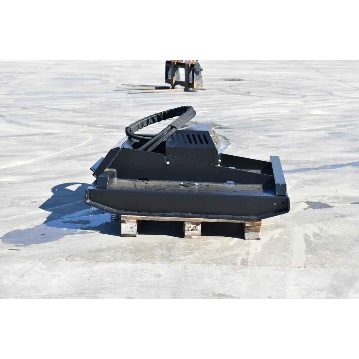 A black and yellow loflin fabrication mini skid steer brush cutter attachment, likely a loader bucket or scraper component, resting on a wooden pallet on a concrete surface.