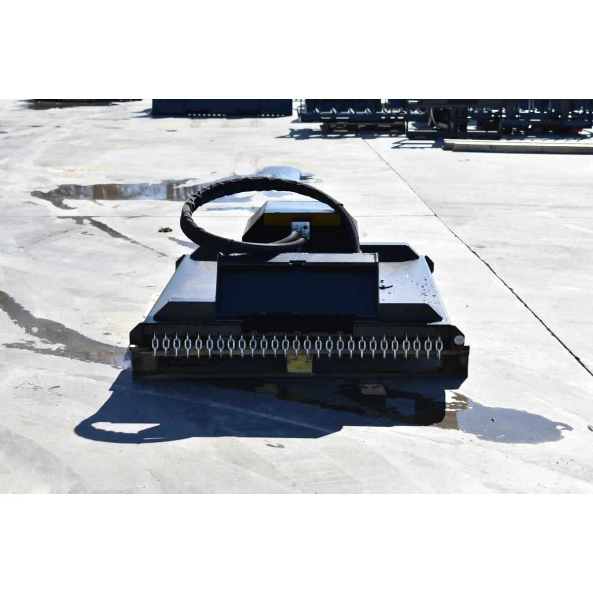 A heavy-duty black loflin fabrication mini skid steer brush cutter with a curved black handle or loop on top, photographed outdoors on a concrete surface.