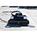 A heavy-duty black loflin fabrication mini skid steer brush cutter with a curved black handle or loop on top, photographed outdoors on a concrete surface.