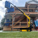 Yellow movex tt 270 stair climber lifting a large blue object on a grassy area in front of a house.