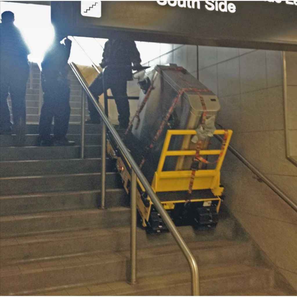 Person using a movex twin track tt 66 on a staircase with 'South Side' sign above.