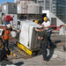 Workers movinga large piece of equipment with a movex tt66 twin track carrier on a rooftop with city buildings in the background.