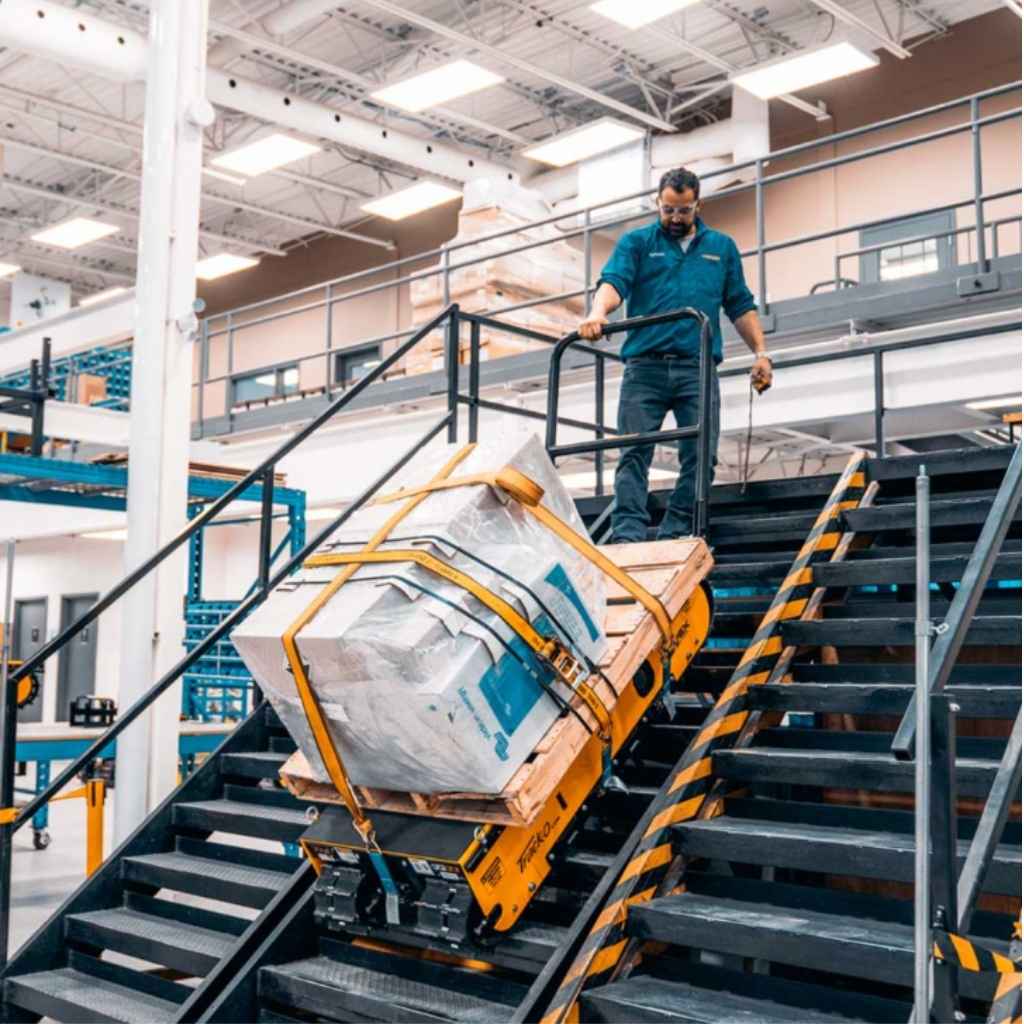 Person using a Movex TT 66 to move a pallet with a large box in a warehouse.