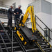 Two workers operating a yellow movex stair climber crane tt270 on a set of stairs.