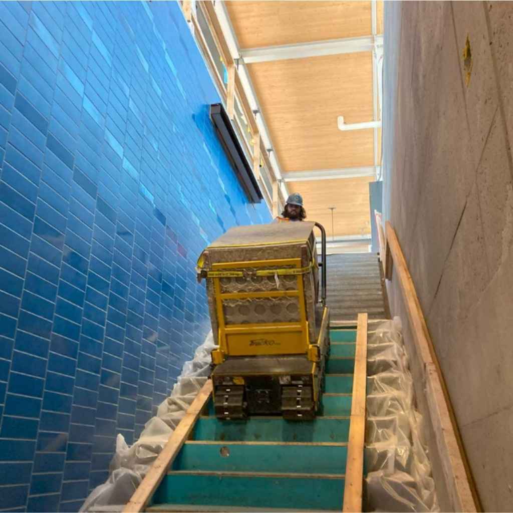 Person using a movex twin track 66 on a set of blue-tiled stairs.