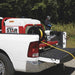 White truck with a NorthStar 100 gal skid sprayer on the back, attached to a trailer with equipment.