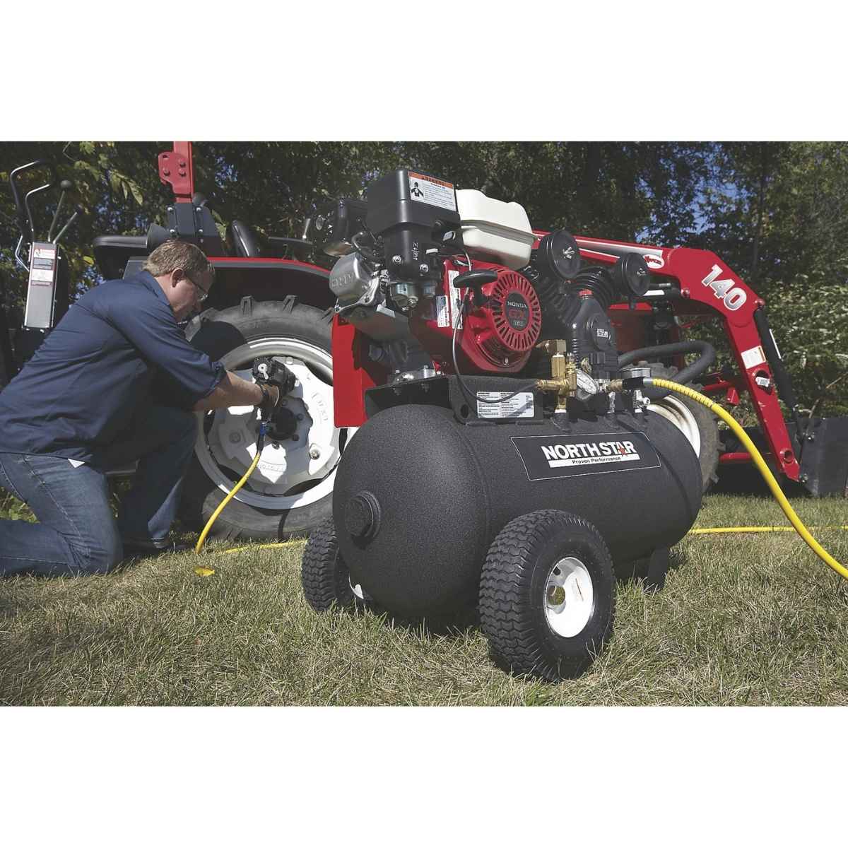Person using a NorthStar 20 gal gas air compressor on a lawn.