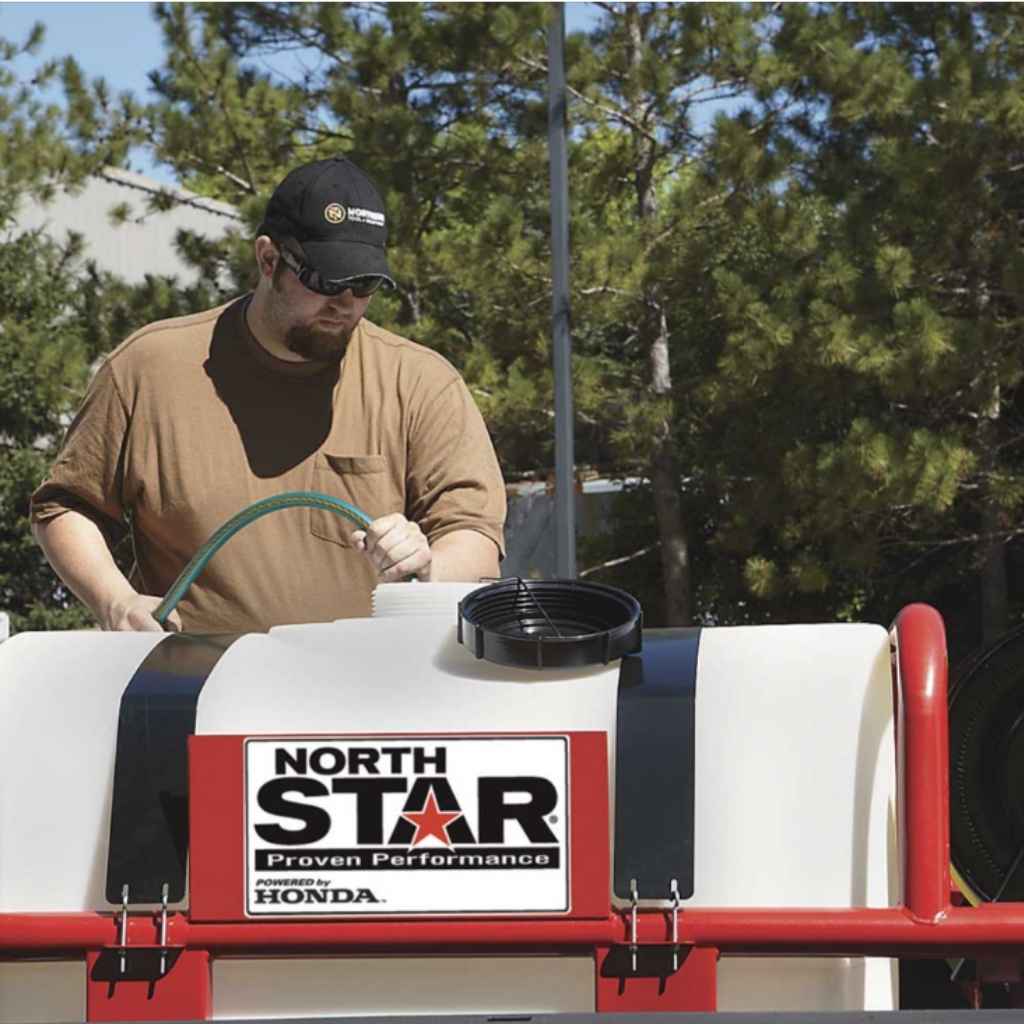 Person using a hose on a NorthStar 200 gallon skid sprayer with trees in the background