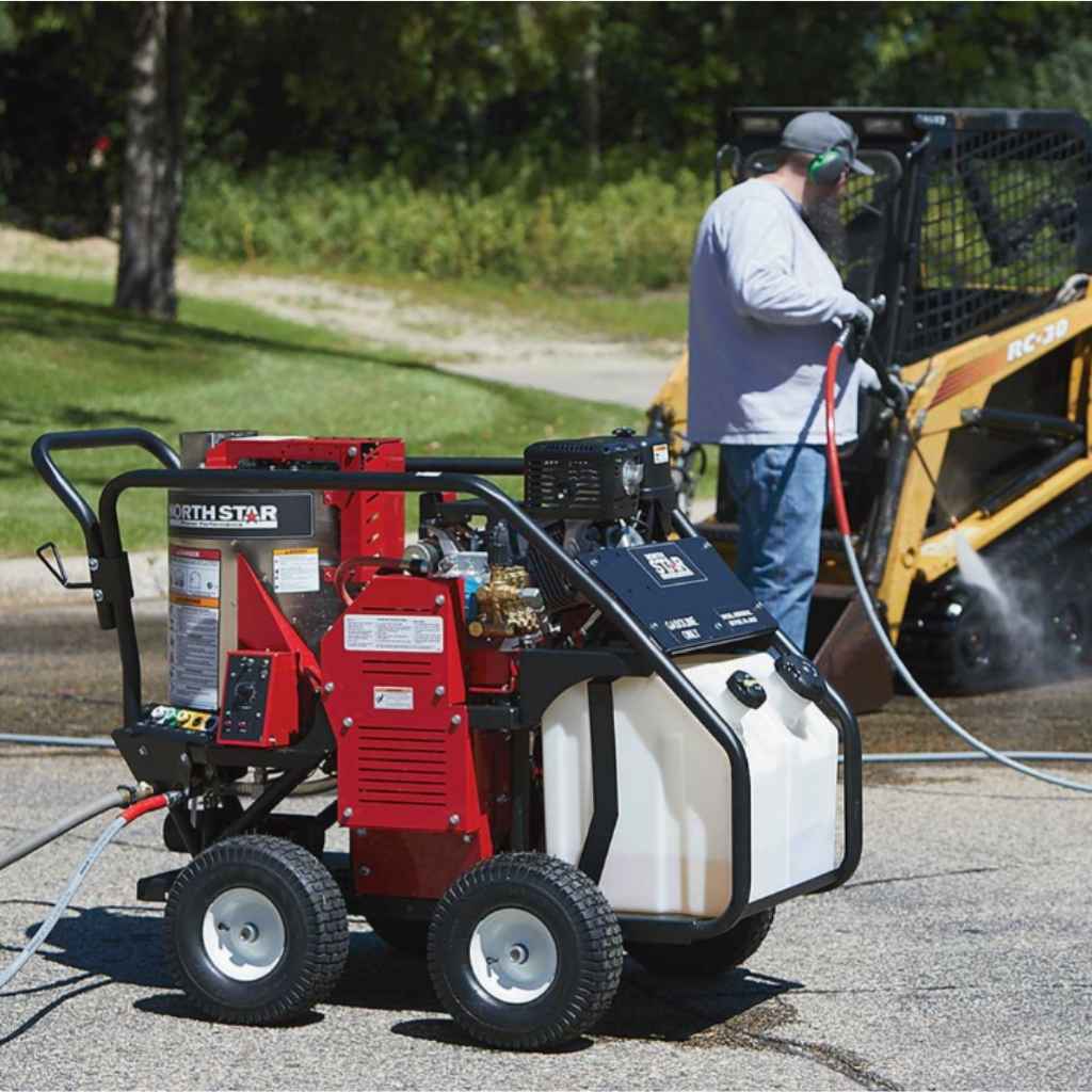 Red and black northstar 3500 psi hot water pressure washer 3.5 GPM on a driveway with a person using it in the background.