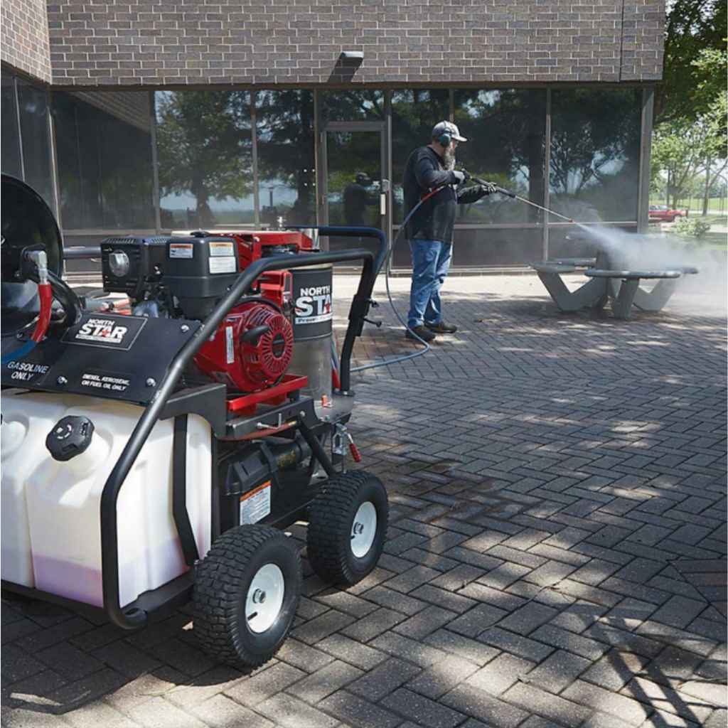 Person using a northstar 3500 psi hot water commercial pressure washer on a sidewalk next to a machine with 'Star' branding.dd