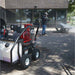 Person using a northstar 3500 psi hot water commercial pressure washer on a sidewalk next to a machine with 'Star' branding.dd