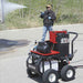 person using a northstar hot water 2750 psi pressure washer on a semi trailer with a concrete ground and trees in the background during the daytime.